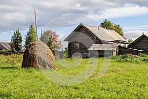 Old log house with haystack in the village, sunny autumn day