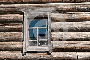 Old log house wood wall with window tilted on one side