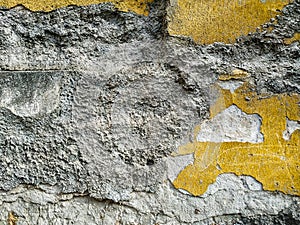 Old looking wall with signs of decay and layers of facade showing on the outdoors building wall with cement and other surface