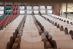Old loom, spinning machine, rows of white and colored cotton threads