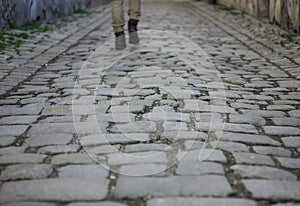 Old macadam street with lonely walker's legs as a background