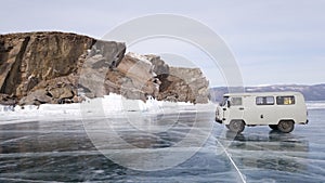 An old machine of high permeability carries tourists on the ice of the frozen lake Baikal. A winter journey through Russia.