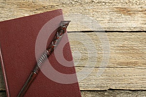 Old magic wand and book on wooden table, top view. Space for text