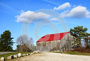 Old Maine country barn, bright red roof, blue sky