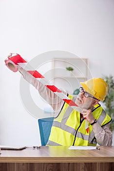 Old male architect holding caution tape