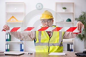 Old male architect holding caution tape