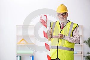 Old male architect holding caution tape