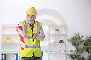 Old male architect holding caution tape