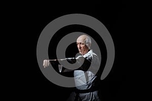 Old male athlete beats a punch with a hand on a black background