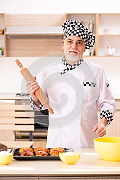 The old male baker working in the kitchen