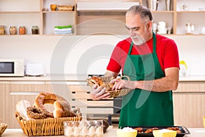 The old male baker working in the kitchen