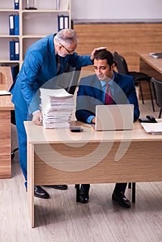 Old male boss and his young male assistant in bullying concept