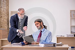 Old male boss and young employee working in the office