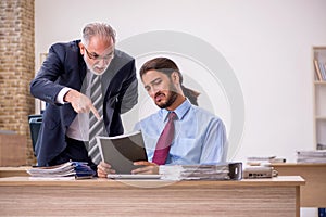 Old male boss and young employee working in the office