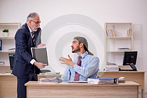 Old male boss and young employee working in the office