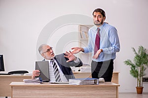 Old male boss and young employee working in the office