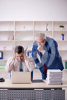 Old male boss and young male employee in bullying concept