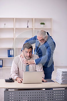 Old male boss and young male employee in bullying concept