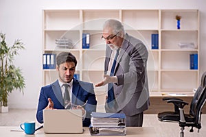 Old male boss and young male employee in the office