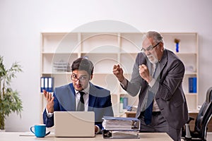 Old male boss and young male employee in the office