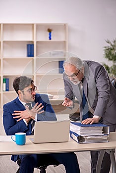 Old male boss and young male employee in the office