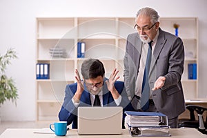 Old male boss and young male employee in the office