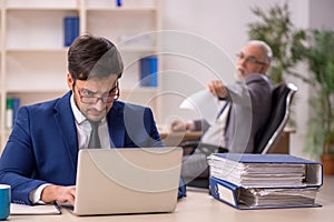 Old male boss and young male employee in the office