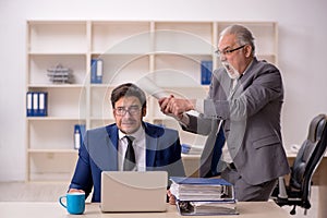 Old male boss and young male employee in the office