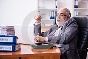 Old male businessman employee working in the office