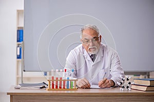 Old male chemistry teacher in the classroom