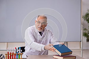 Old male chemistry teacher in the classroom