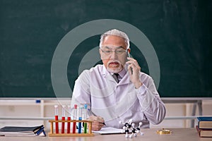 Old male chemistry teacher in the classroom