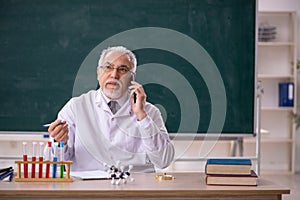 Old male chemistry teacher in the classroom