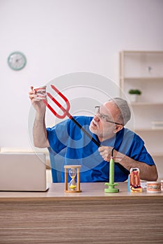 Old male dentist working in the clinic