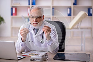 Old male doctor holding goniometer in the clinic