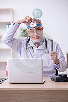 Old male doctor otologist working in the clinic