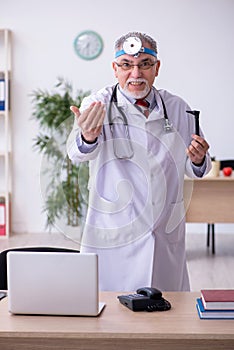 Old male doctor otologist working in the clinic