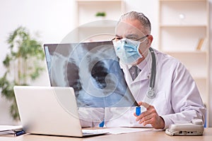 Old male doctor radiologist working in the clinic during pandemi