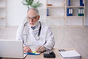 Old male doctor in telemedicine concept