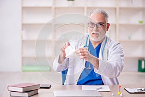 Old male doctor wearing mask in the clinic