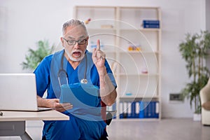 Old male doctor working in the clinic