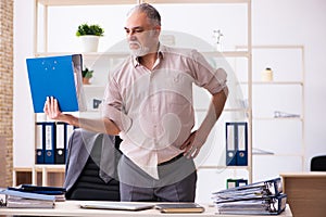 Old male employee doing physical exercises at workplace