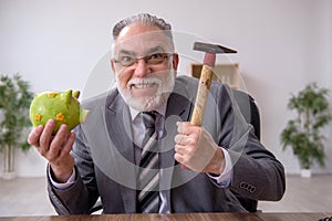 Old male employee holding hammer in budget planning concept