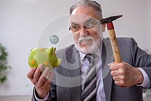 Old male employee holding hammer in budget planning concept