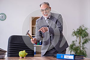 Old male employee holding hammer in budget planning concept