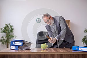 Old male employee holding hammer in budget planning concept