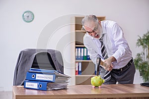 Old male employee holding hatchet in budget planning concept