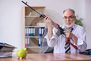 Old male employee holding rifle in budget planning concept