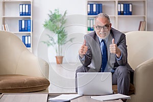 Old male employee sitting on arm-chair