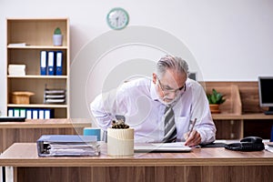 Old male employee suffering from radiculitis at workplace